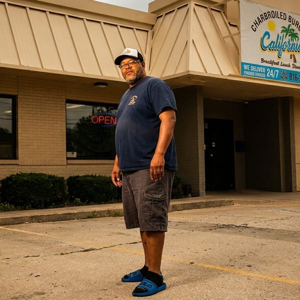 Man standing in front of California Charbroiled Burgers restaurant with an "Open" sign in the window.